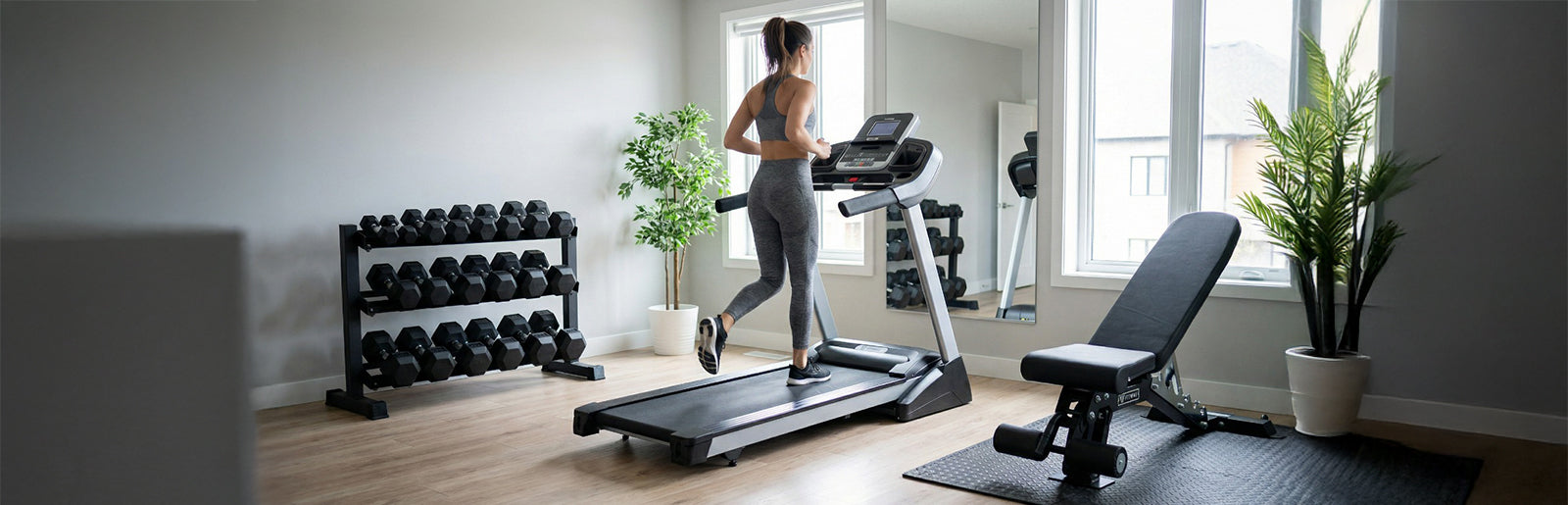 Woman exercising on a treadmill in a home gym with weights and exercise bench.
